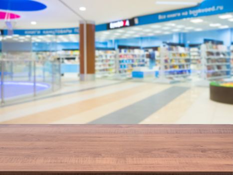 Brown wooden board empty table in front of blurred shopping mall - can be used for display or montage your products. Mockup for display of product.