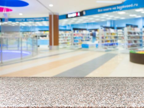 Marble board empty table in front of blurred shopping mall - can be used for display or montage your products. Mockup for display of product.