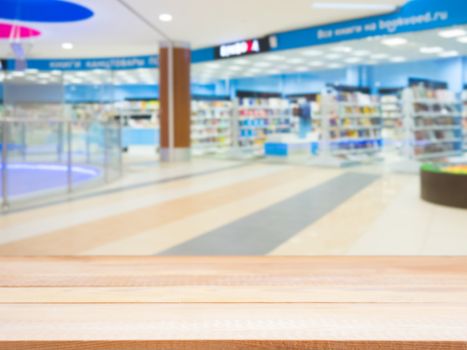 Light wooden board empty table in front of blurred shopping mall - can be used for display or montage your products. Mockup for display of product.