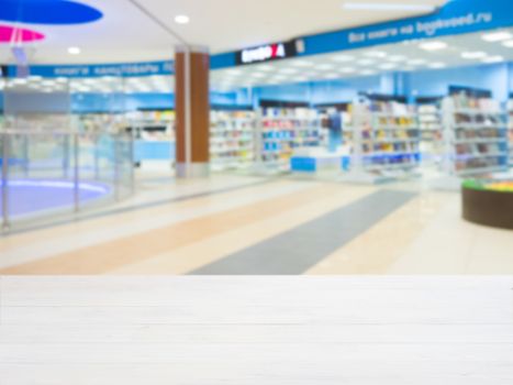 White wooden board empty table in front of blurred shopping mall - can be used for display or montage your products. Mockup for display of product.