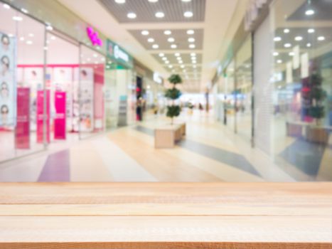 Light wooden board empty table in front of blurred shopping mall - can be used for display or montage your products. Mockup for display of product.