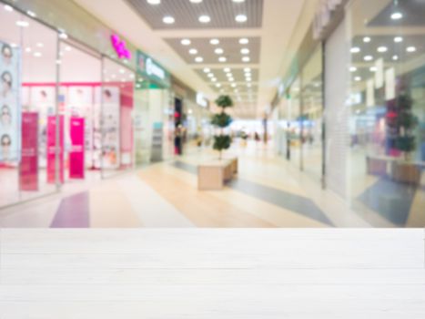 White wooden board empty table in front of blurred shopping mall - can be used for display or montage your products. Mockup for display of product.