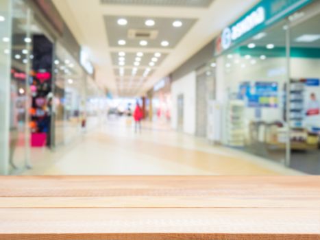 Light wooden board empty table in front of blurred shopping mall - can be used for display or montage your products. Mockup for display of product.