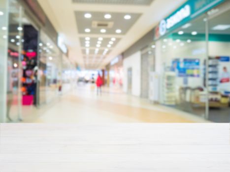 White wooden board empty table in front of blurred shopping mall - can be used for display or montage your products. Mockup for display of product.