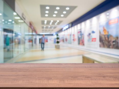 Brown wooden board empty table in front of blurred shopping mall - can be used for display or montage your products. Mockup for display of product.