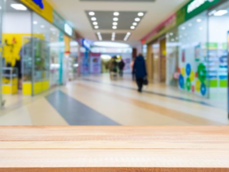 Light wooden board empty table in front of blurred shopping mall - can be used for display or montage your products. Mockup for display of product.