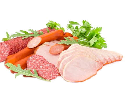 Sliced boiled smoked pork loin and ham, partly sliced salami and hunting sausages with arugula and parsley closeup on a light background
