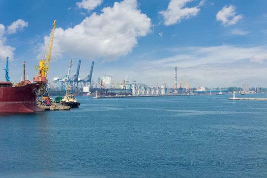 Part of the sea cargo port with several berth with different harbor cranes and bow of the ship in the foreground
