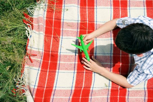 Boy playing with green toy plane