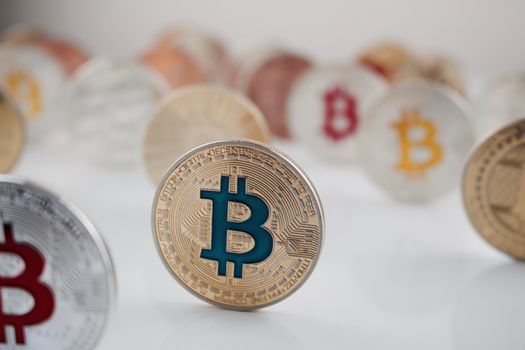 Cryptocurrency physical blue bitcoin coin near other bitcoins on the table.