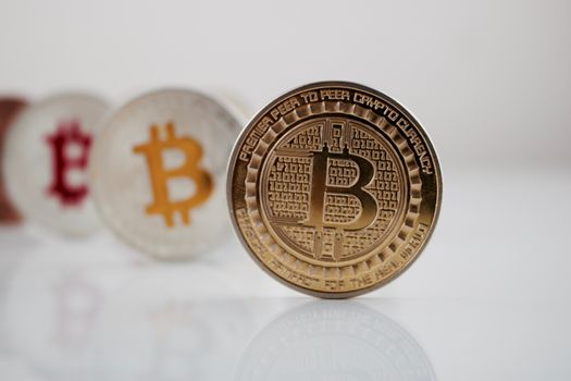 Digital currency physical gold bitcoin coin on white table near bitcoins.