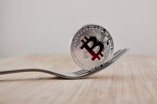 Cryptocurrency physical silver bitcoin coin with red sign on the wooden board.