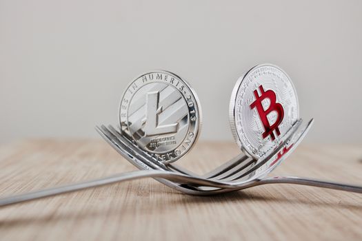 Digital currency physical silver bitcoin and litecoin on the wooden board. Fork concept.