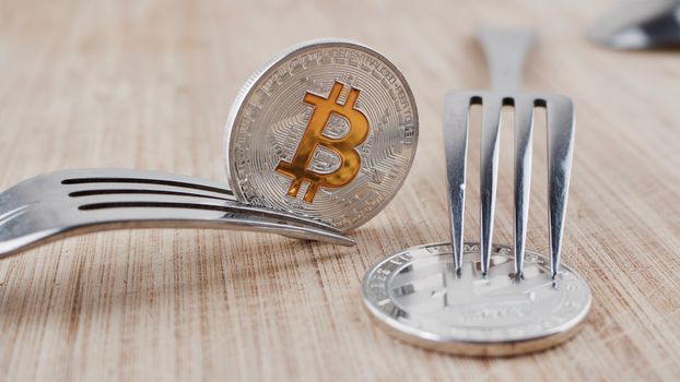 Digital currency physical silver bitcoin coin on wooden board near litecoin.