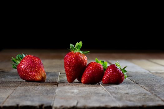 Delicious strawberry in home cooking on wooden table, black background.