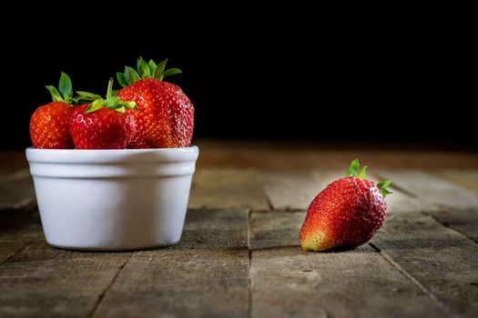 Delicious strawberry in home cooking on wooden table, black background.