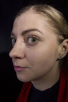 Strange young blonde woman close-up on a black background