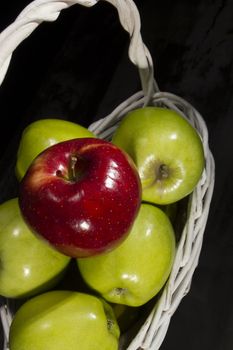 Ripe apples in a wicker basket on a black background