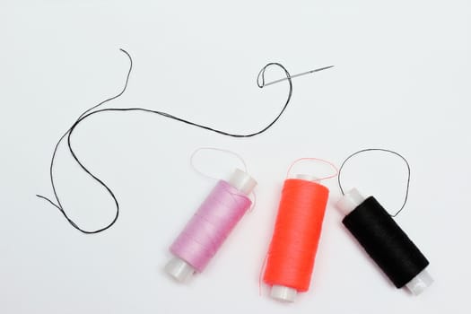 Sewing composition of three coils of thread and sewing needle.