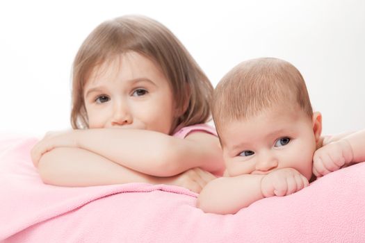 two little girls of the sisters lie on a pink plaid