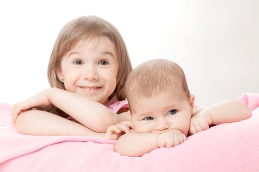 two little girls of the sisters lie on a pink plaid