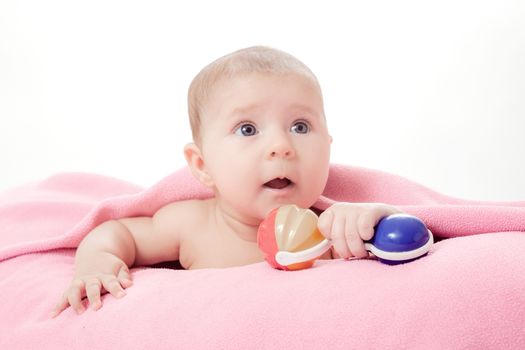 the little beautiful baby under a pink plaid with a rattle in a hand