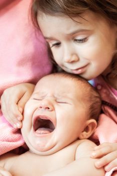 two little girls of the sisters lie on a pink plaid