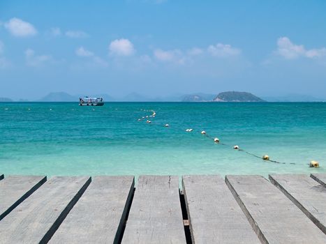 Boardwalk with emerald sea and boat