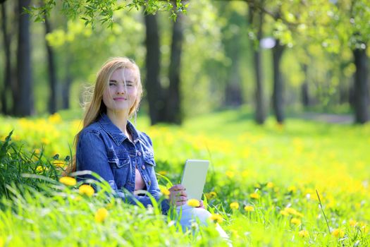 Young woman using tablet in spring park with flowers