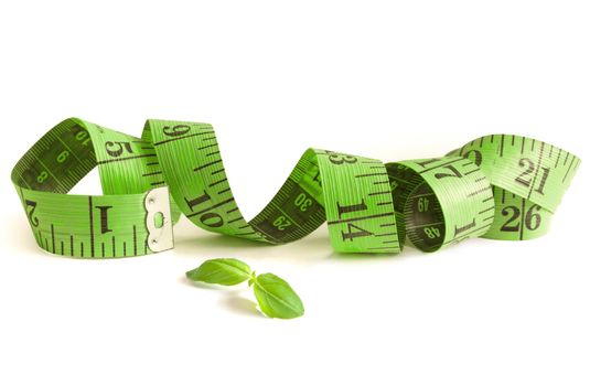 Green measuring tape over a white background with leaf