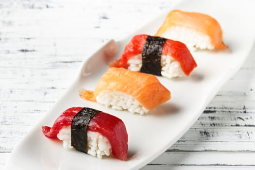 Set of salmon and red tuna Nigiris on white plate over old white wood. Raw fish in traditional Japanese sushi style. Horizontal image.