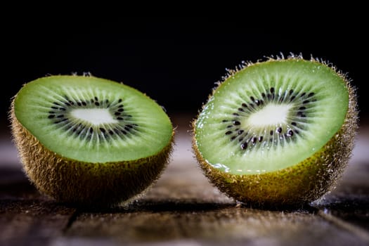 Kiwi in the old kitchen on a wooden table. Black background.