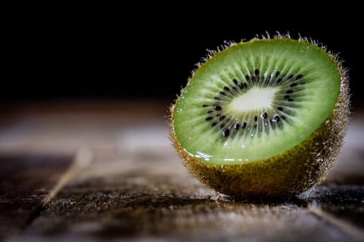 Kiwi in the old kitchen on a wooden table. Black background.