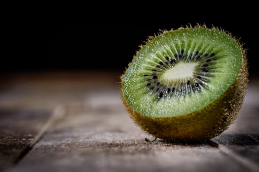 Kiwi in the old kitchen on a wooden table. Black background.