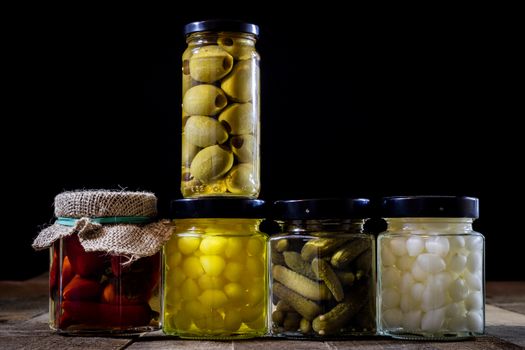 Mortar, vegetables in jars for the winter, wooden table in the old kitchen. Black background.