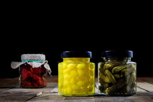 Mortar, vegetables in jars for the winter, wooden table in the old kitchen. Black background.