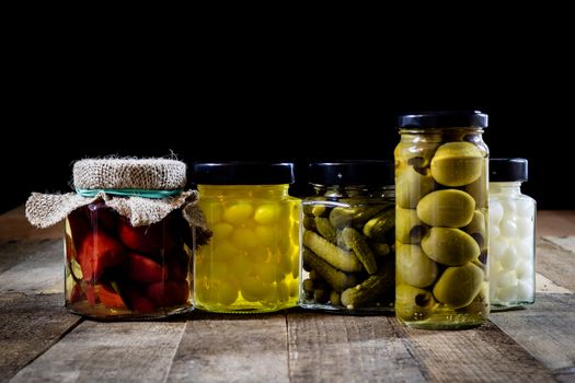 Mortar, vegetables in jars for the winter, wooden table in the old kitchen. Black background.