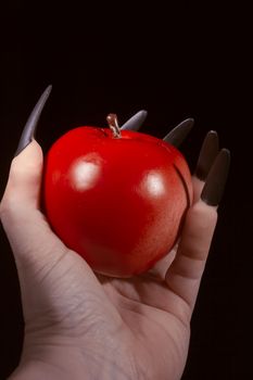 Red apple in the hands of a witch