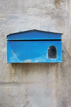 old blue mailbox on cement wall