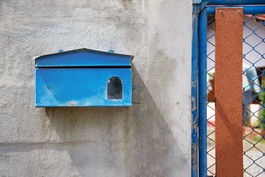 old blue mailbox on cement wall