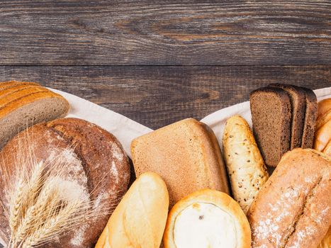 Assortment different types of bread. Rustic style bread on brown wooden table. Top view or flat lay. Copy space.