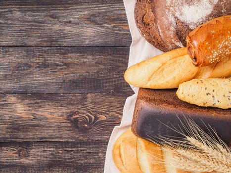 Assortment different types of bread. Rustic style bread on brown wooden table. Top view or flat lay. Copy space.