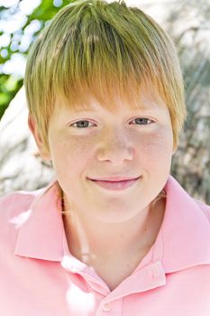 Smiling boy in pink shirt near tree