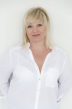 Vertical portrait of blond woman with blue eyes in white