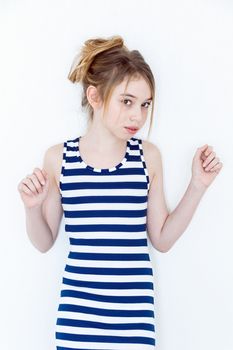 Cute girl eleven years old with blond long hair standing near white wall and upwards hands