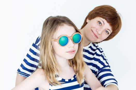 Mother and daughter in green sunglasses playing near white wall