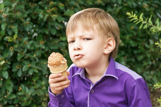 Horizontal photo of blond boy are eating icecream in summer