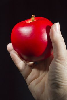 Red apple in hand on a black background