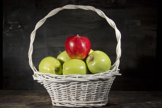 Ripe apples in a wicker basket on a black background