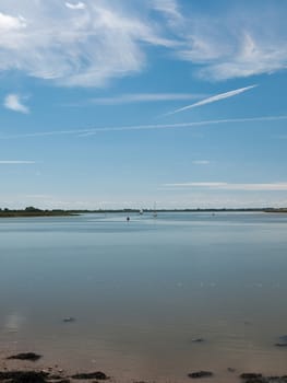 a calm and clear day on a river surface with country in the distance and buoys and boats no people beautiful